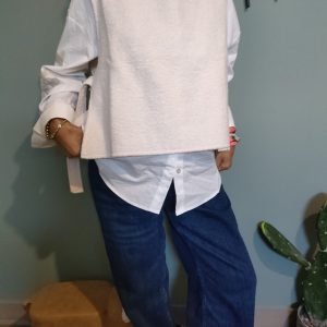 "Look élégant et minimaliste avec un pull sans manches beige sur une chemise blanche, parfait pour un style épuré et moderne."