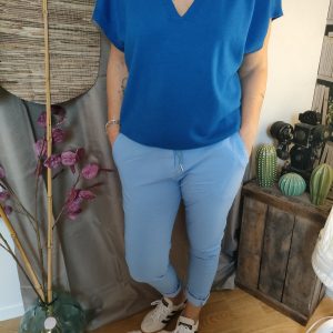 "Look casual chic : top bleu col V, pantalon slim bleu ciel et sneakers modernes pour une allure élégante et décontractée."